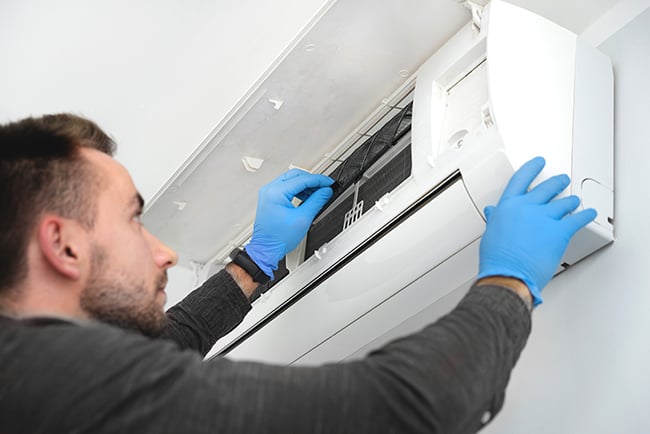Technician replacing filter in air conditioner