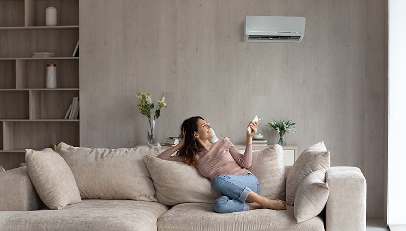 Relaxed young woman turning on air conditioner