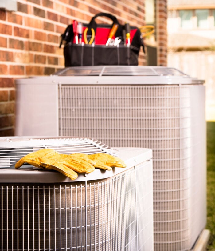 AC-installation HVAC technician's gloves atop a heat pump unit, ready for maintenance and servicing of residential heating systems.